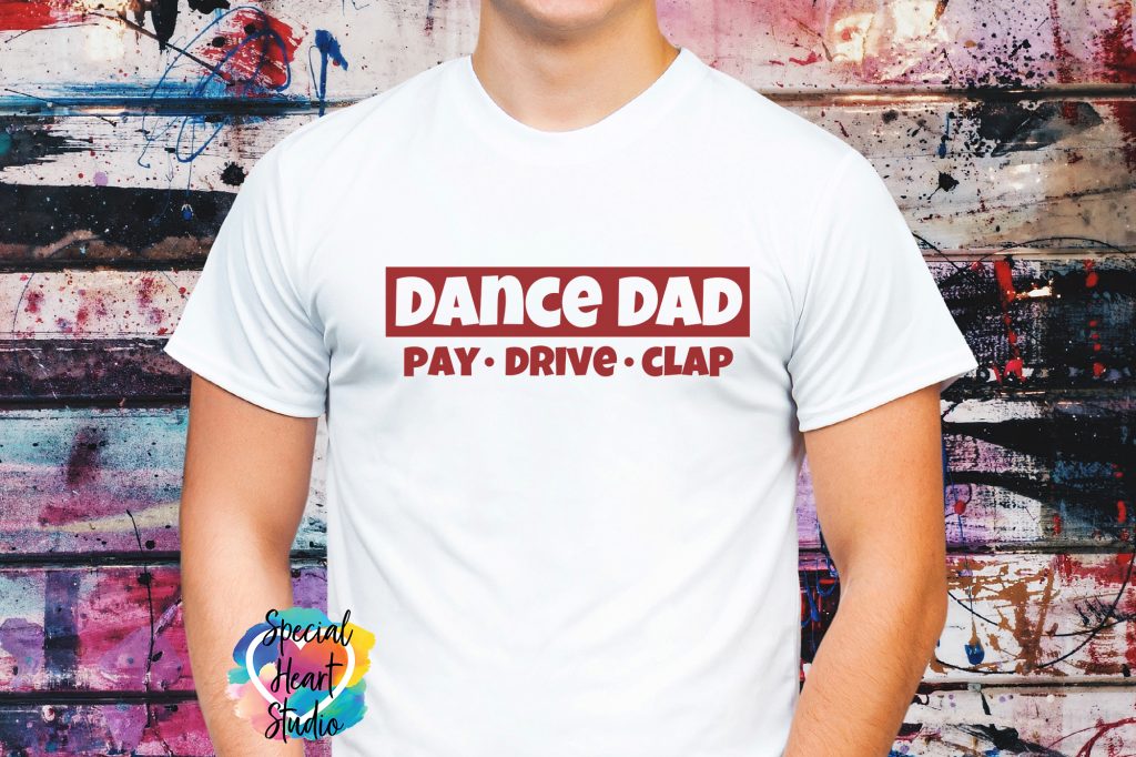 Man's chest wearing white t-shirt with graphic saying Dance Dad. Pay, Drive, Clap