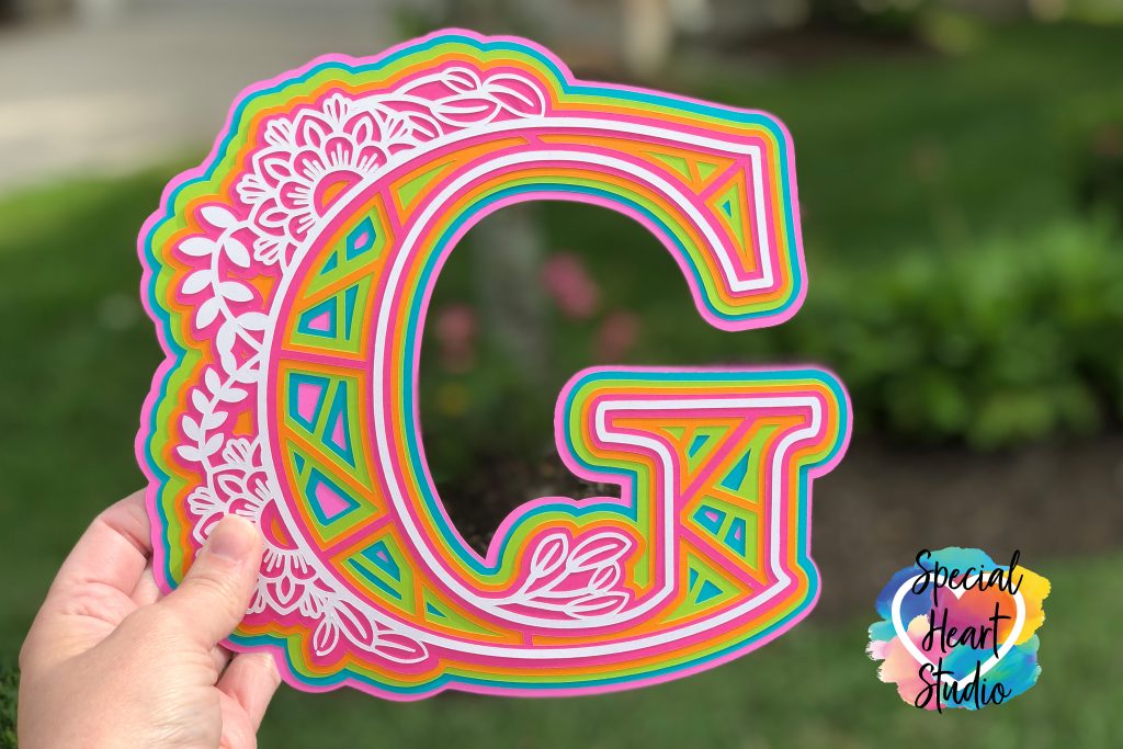 Brightly colored cardstock with letter G cut in a 3D floral mandala style pattern