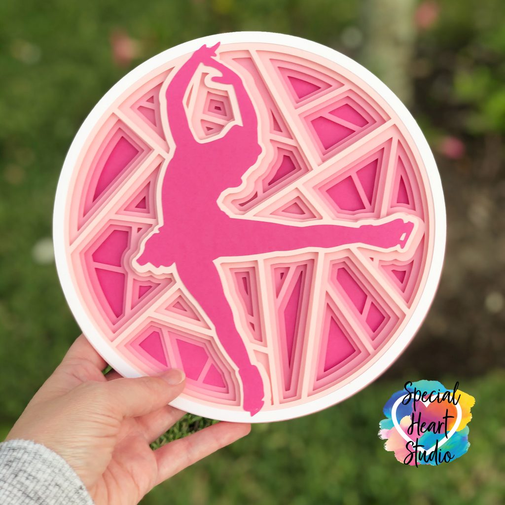 Layers of pink cardstock stacked in a circle with a female figure skater silhouette image