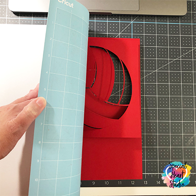 Removing freshly cut cardstock from the Cricut cutting mat. 