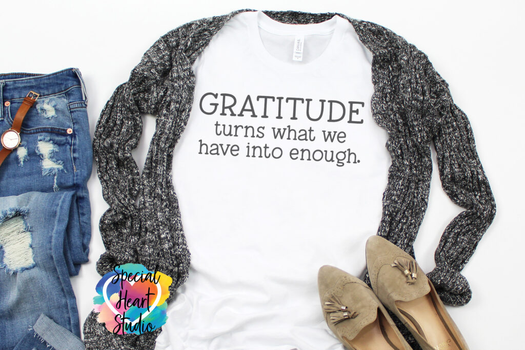 White t-shirt with black writing saying  Gratitude turns what we have into enough